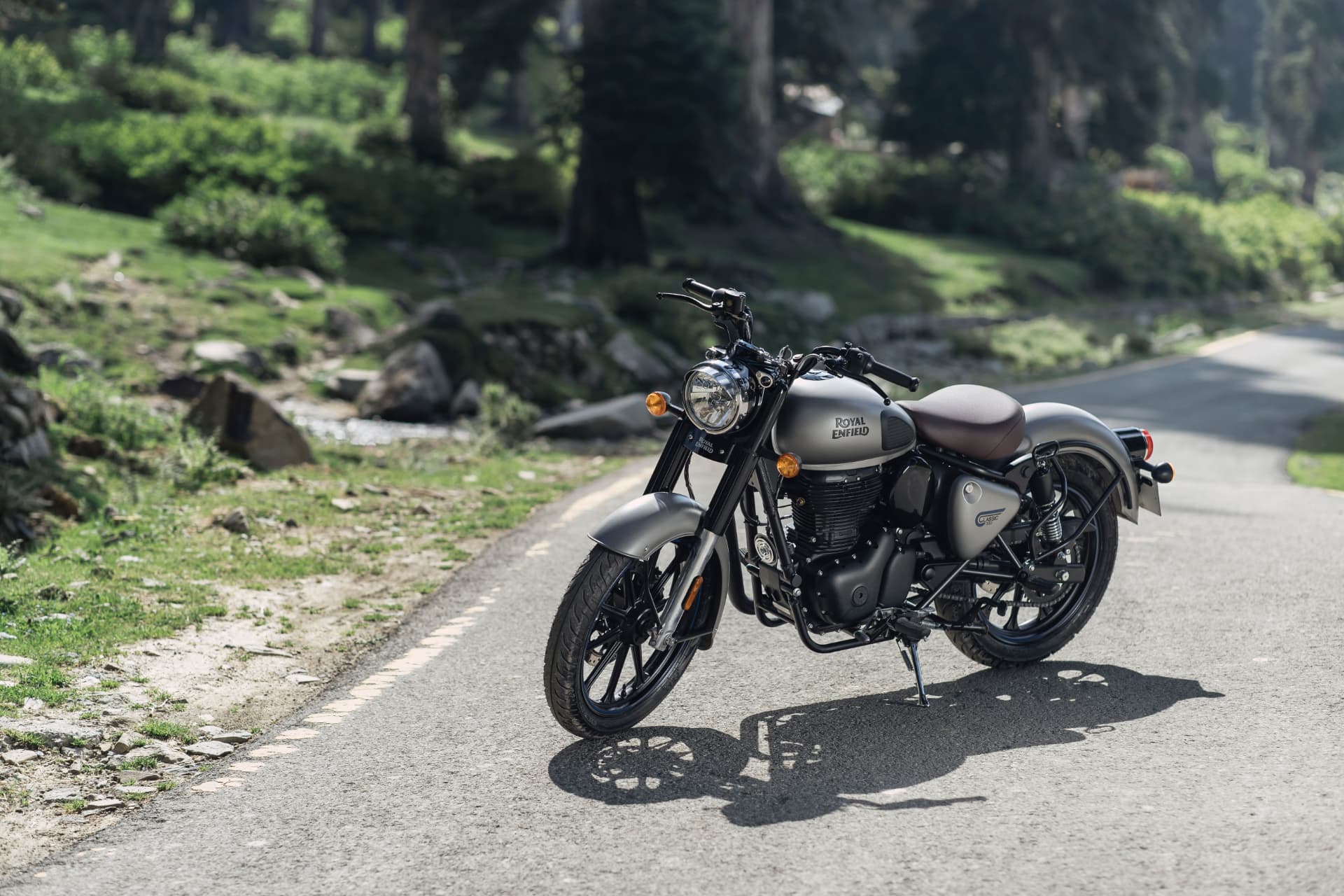 Motocicleta Royal Enfield Classic 350 em estrada de montanha entre árvores